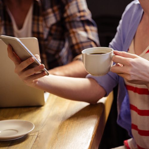 Focus on a cup of coffee and phone at cafeteria